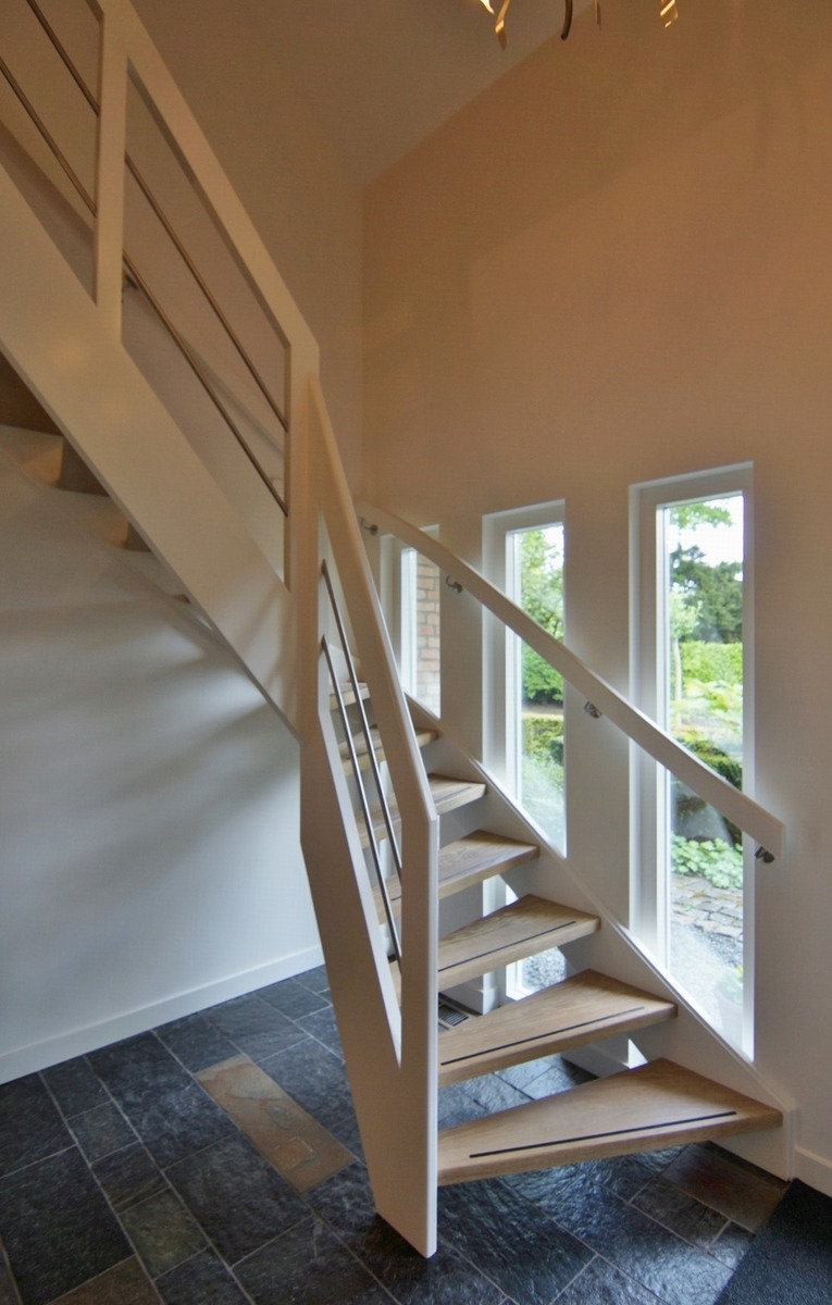 moderne trap,houten trap,Ulvenhout,Breda,Nederland, zicht op de aanvang van deze trap,met eiken treden,open trap,voorzien van antislip, treden tussen de beuken trapwangen die we wit geschilderd hebben,zicht op de witte muurgreep aan de muurzijde