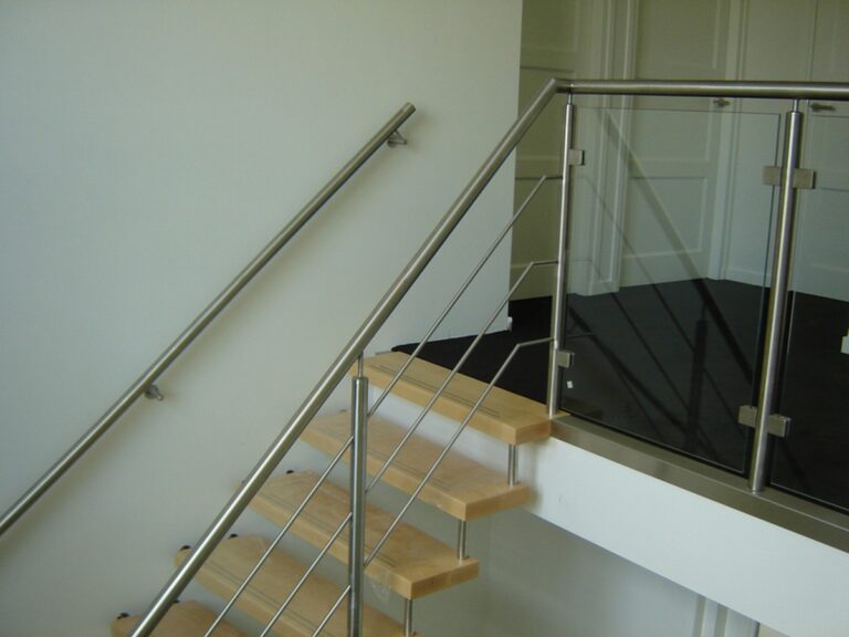 zwevende trap,houten trap,moderne trap,RVS,glas,Goeree-Overflakkee,Nederland,zicht op de aankomst van de trap op de verdieping,zicht op de glazen balustrade met RVS en de metalen muurgreep in RVS aan de muurkant van de trap